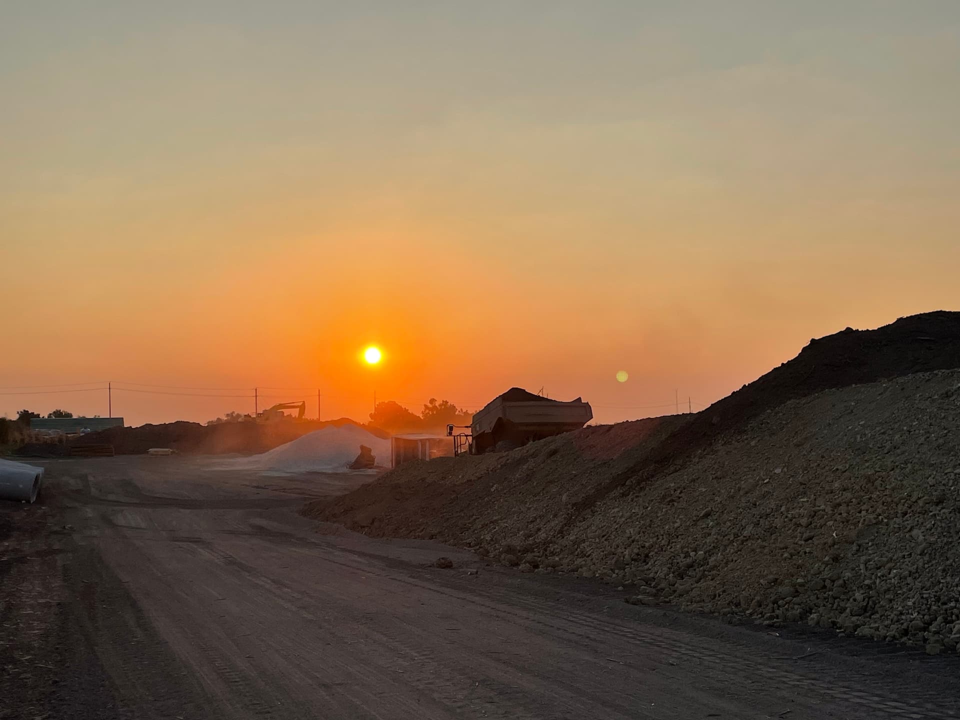 Earthmoving equipment on a civil construction site at sunset